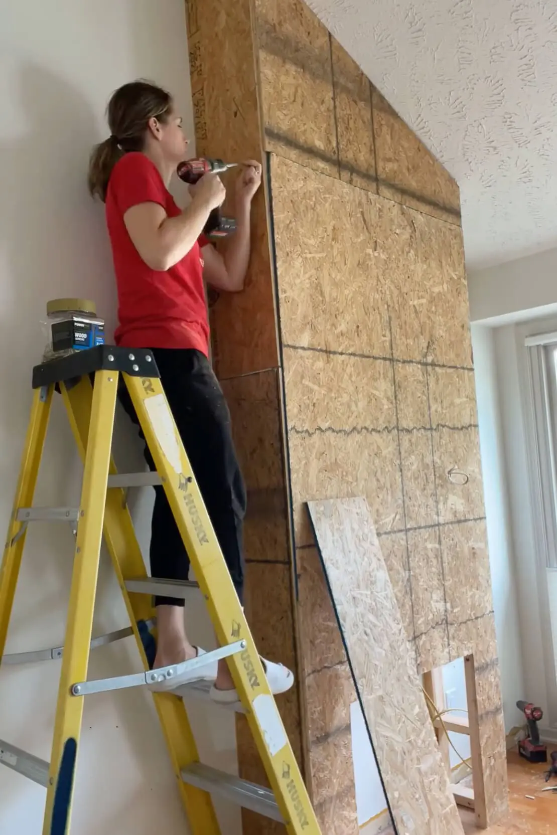 Installing OSB sheeting over the fireplace frame using a power drill.